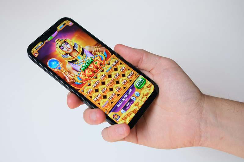 Three diverse hands holding smartphones showing cheerful casual game interfaces, smiling together in natural light